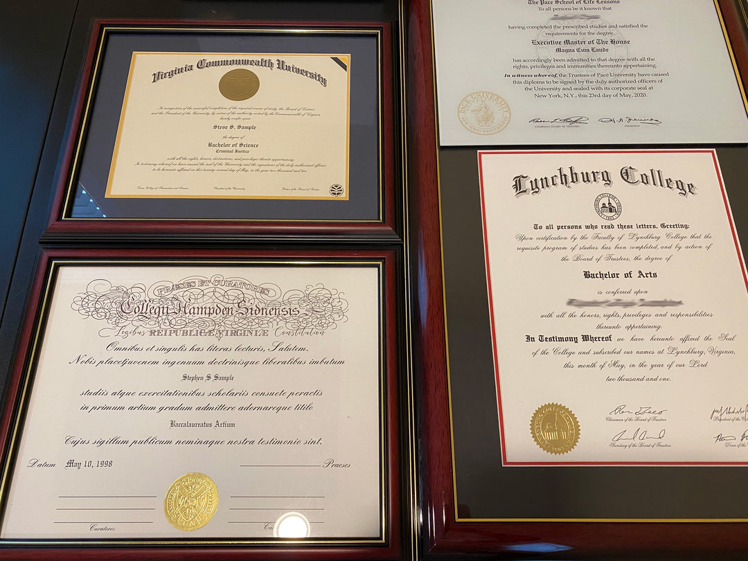 Four framed replacement diplomas from different colleges on a wooden surface